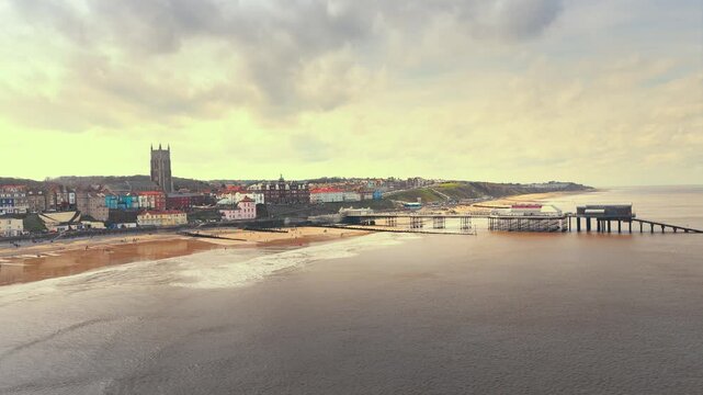 Seaside views of the holiday town of Croma on the Norfolk coast. Sandy beach and sea. Holiday destination, vintage photograph. North Sea coastline, Chapel, church and pier on the promenade, tourists.