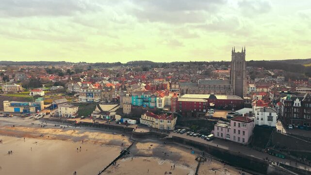 Seaside views of the holiday town of Croma on the Norfolk coast. Sandy beach and sea. Holiday destination, vintage photograph. North Sea coastline, Chapel, church and pier on the promenade, tourists.