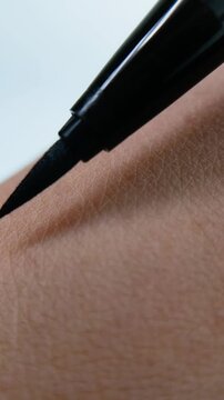 Eyeliner tested on skin in close up showing natural skin texture, highlighting stroke result and product pigmentation, suitable for beauty themes and face makeup product presentation.