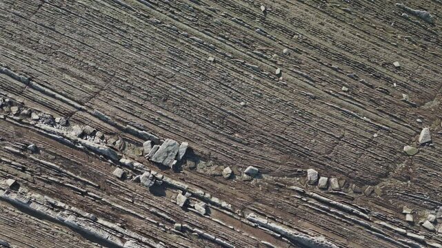 Dramatic aerial top down perspective of the unique flysch rock formations at Sakoneta beach, a stunning geological feature on the Basque Coast Geopark in Zumaia, revealing its layered patterns
