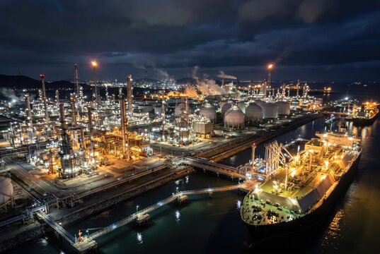 LNG terminal at night, illuminated plant, tanker at dock, energy independence concept, liquefied natural gas facility