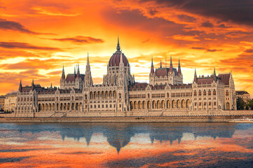 The Hungarian Parliament Building stands majestically along the Danube River under a vibrant orange sunset sky. © Denis Rozhnovsky
