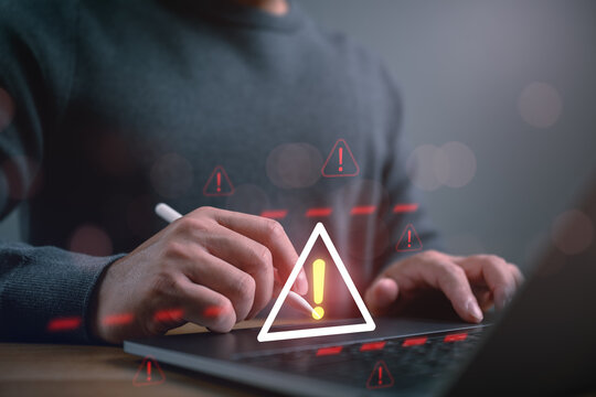 Close-up of person using stylus on laptop with warning icons, representing cybersecurity alert, system risk, data breach, online threat detection, and digital security incident response.