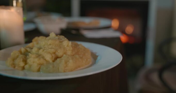 Close-up Dish of Mashed Potato Puree on Table Near Fireplace. 4K 10-bit
