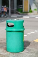 Obraz premium Green street trash bin on urban sidewalk
