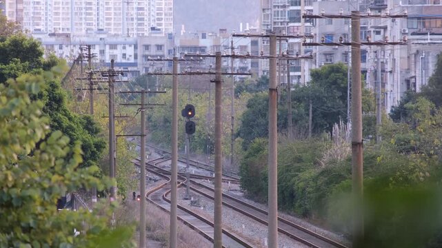 Aging, non-electrified railway tracks branching through multiple junctions in a Chinese city. Weathered wooden telegraph poles line the tracks alongside an old signal light. Liuzhou, China.