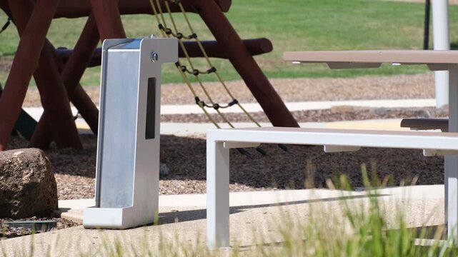 Stainless steel dual-level drinking fountain in a well-maintained Australian suburban public park, featuring a bubbler for humans at the top and a low-level water trough for dogs at the base