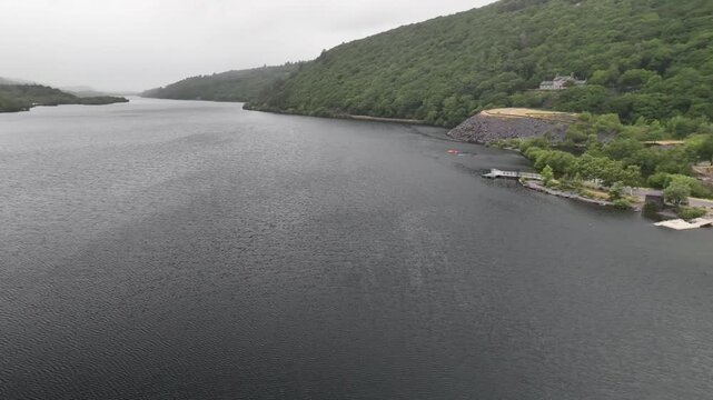 Aerial Flight Over Llyn Padarn Lake Toward Boathouse Shoreline Wales