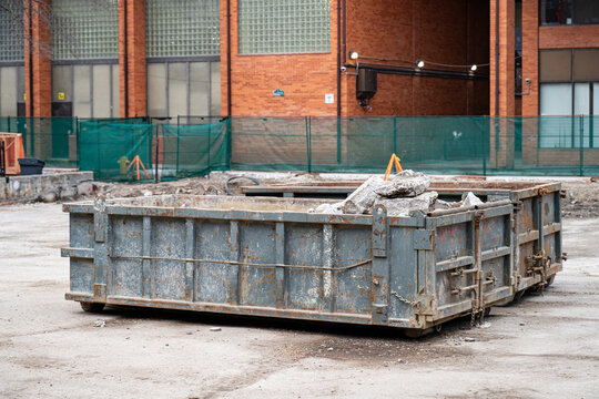 Construction dumpster filled with debris at building site.