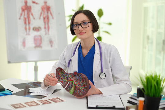 Caucasian female clinician reviewing ultrasound photos next to liver model, explaining imaging findings and care plan to patient