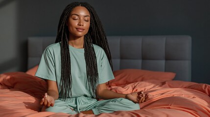 Fototapeta premium Woman meditating cross legged on bed in bedroom setting