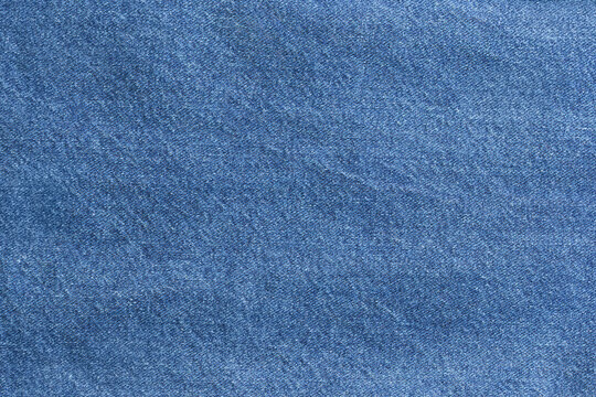 Indigo woven textile for designers. Neutral background showcasing indigo dyed denim material texture. Fabric swatch featuring dense woven blue denim pattern with classic indigo coloration