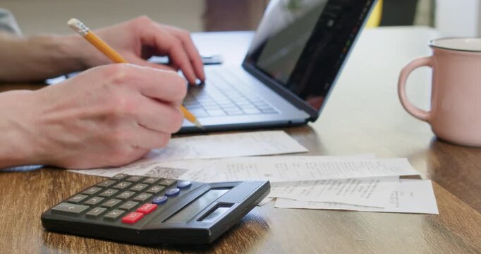 Businessman types on laptop calculating regular payments at workplace closeup. Entrepreneur freelancer plans budget and counts taxes with digital devices at home