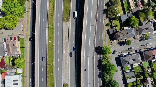rone shot of a complex motorway junction with multiple curved lanes and flowing traffic surrounded by suburban buildings and greenery.