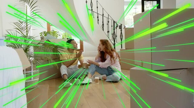 Couple unpacking on floor, woman showing then handing object to man while green streaks radiate