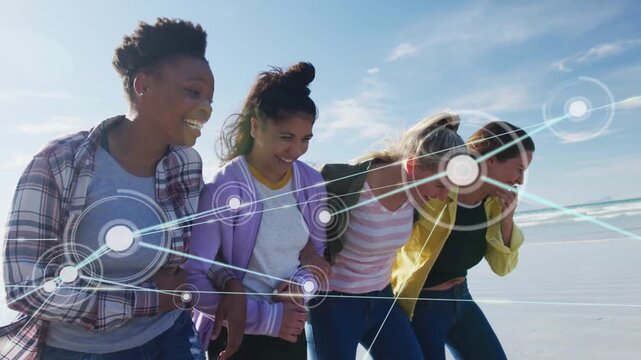 Four women linked arms walking beach, nodes growing, tilting camera, lifting heads, showing tech