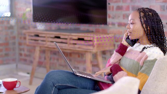 Woman answering ringing phone while typing on laptop and handling remote business tasks from chair