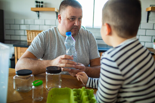 Father teaching child about recycling in home kitchen