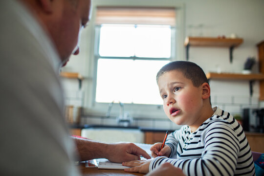 Father helping son with homework at kitchen table