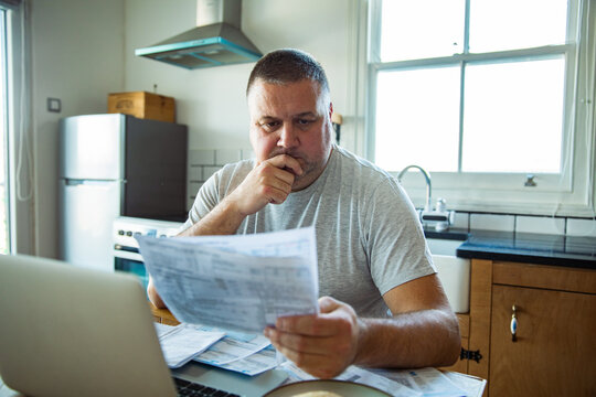 Concerned man reviewing bills at kitchen table