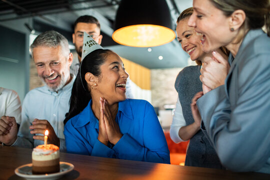 Coworkers celebrating birthday with cake in office