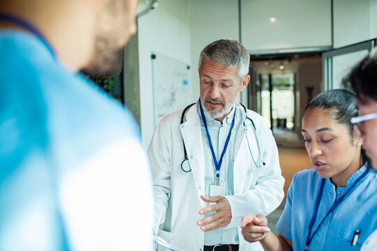 Senior doctor leading medical team discussion in hospital corridor