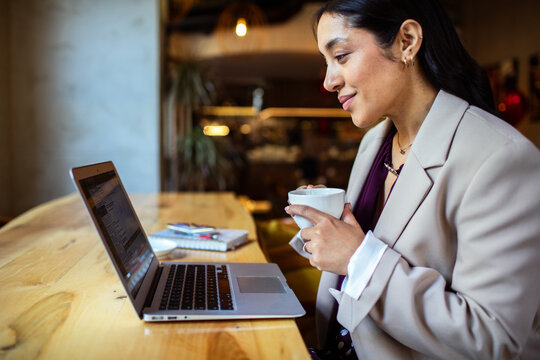 Businesswoman using laptop and drinking coffee in cafe