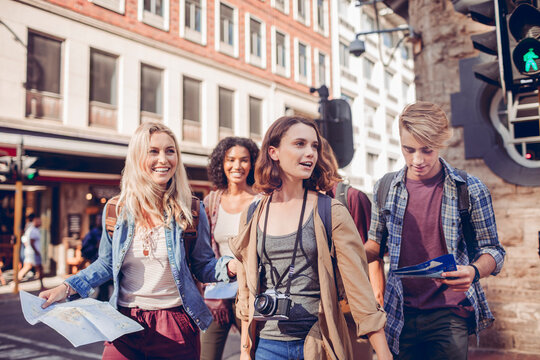 Young friends sightseeing with maps on city street