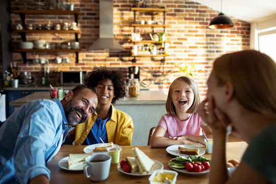 Happy family laughing over breakfast in home kitchen