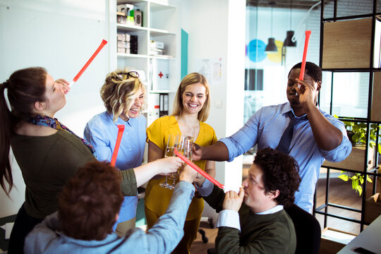 Coworkers celebrating success with champagne in modern office