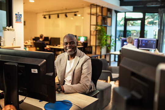Smiling businessman working at computer in modern open-plan office