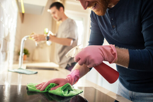 Two men cleaning kitchen together at home