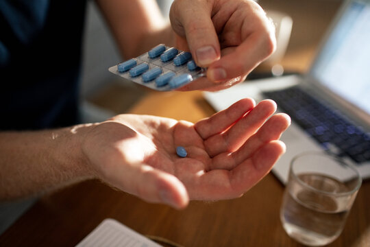 Person taking blue pill at home office desk