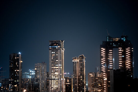 Modern highrise multi storey skyscrapers at night with lights shining through showcasing growth of apartments, buildings, houses and shopping centers in cities like gurgaon, delhi, bangalore, hyderaba