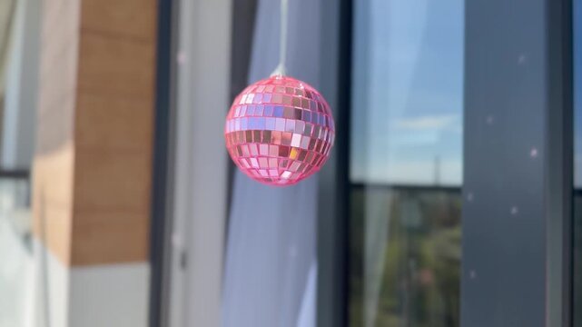 Pink disco ball hanging outdoors with soft movement