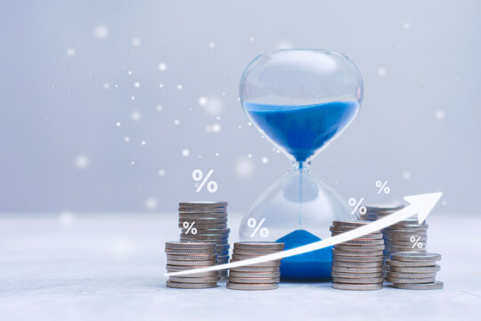 Stacks coins with percentage symbols and hourglass representing time and increasing interest rates with upward arrow. Concept for investment growth, savings over time, banking and financial planning.
