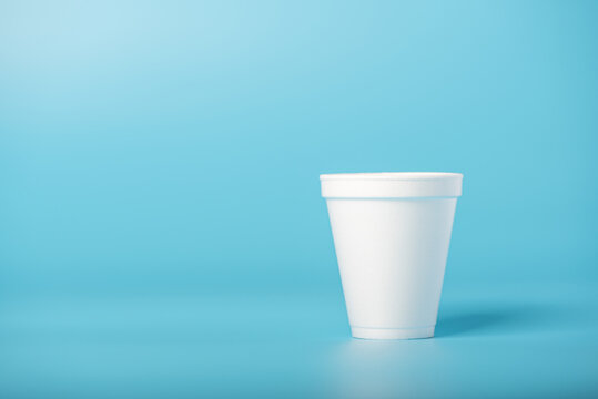 White cup, a white styrofoam cup on a blue background, selective focus.