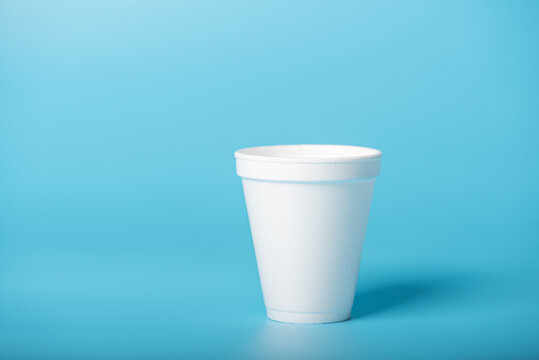 White cup, a white styrofoam cup on a blue background, selective focus.