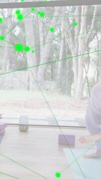 Vertical video: Woman side-bending on blue yoga mat causing green dots on window showing form