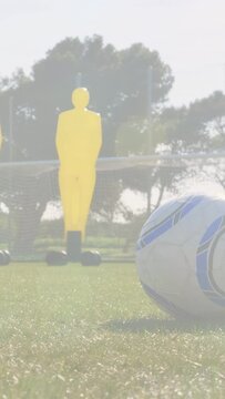 Vertical video: Approaching player running past ball, initiating soccer drill with yellow mannequin