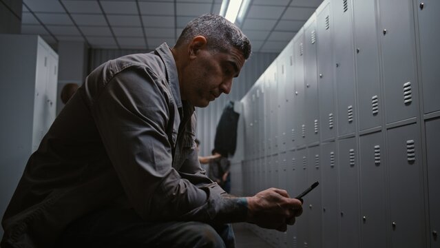 Managing Time And Schedule. Professional Industrial Worker Removes Safety Helmet, Checks Watch and Types Message on Smartphone in Modern Factory Dressing Room. Concept of Managing Time and Schedule.