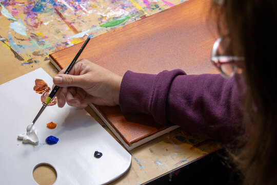 Art workspace with artist, flat lay overhead view, picking up paint 