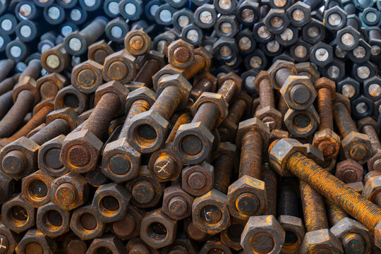 A pile of large rusted industrial steel bolts and nuts at a construction site