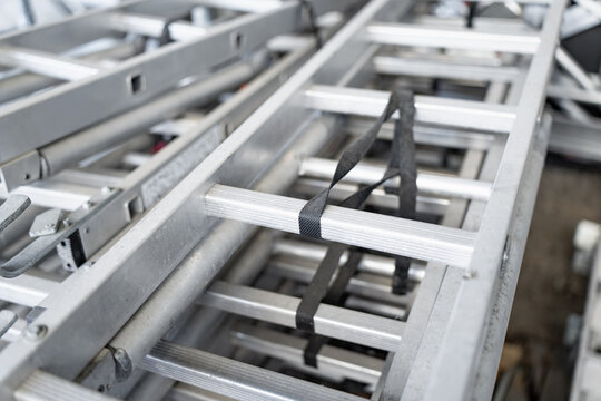 Professional aluminum extension ladders stacked in an industrial warehouse for building maintenance and construction site logistics during an urban development project