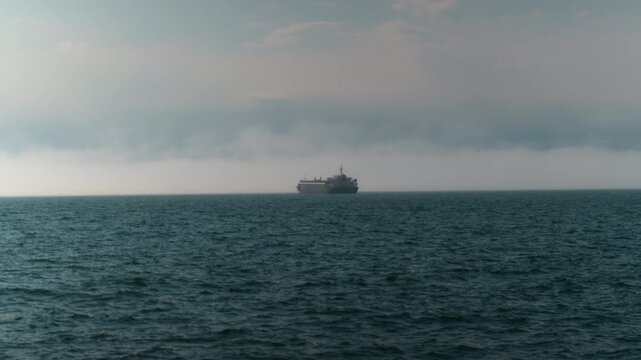 tropical seascape of sailing kargo tanker ship in sea with dark clouds