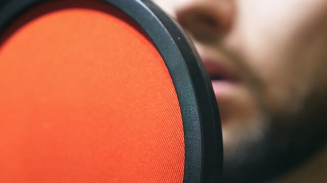 Unrecognizable male singer in headphones singing song at sound studio. Young man emotionally recording new melody or song. Working of creative musician. Show business concept. Slow motion