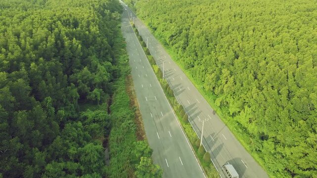 Aerial tracking shot from behind a cyclist in Can Gio forest, drone overtaking and transitioning to a 90-degree top-down view. Bus, sedan, and motorbikes passing the cyclist on Rung Sac road