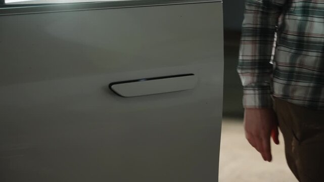 Close-up of a modern car door with flush integrated handle on a sleek metallic white exterior, showcasing smooth body lines, reflections, and refined automotive design details.