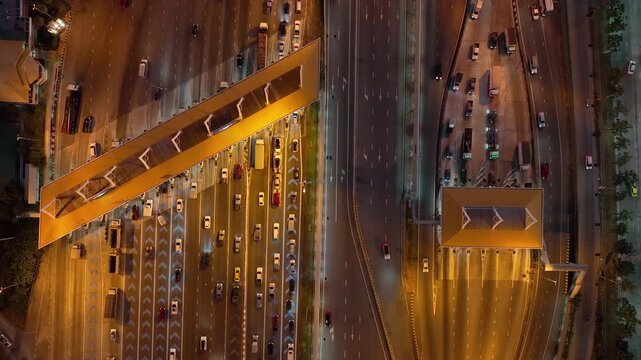Aerial view of traffic on highways and toll booths at night.