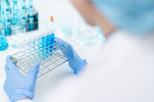 hand of scientist hold test tube with liquid chemical water to recheck experiment result in laboratory, doctor with blue glove research and analyze biochemistry for healthcare and medical innovation